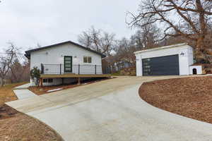 View of property exterior with brick siding, an outbuilding, a wooden deck, and a garage