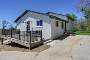 White brick exterior with black trim and gutters, featuring a raised front deck with black railings