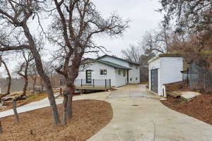 View of front facade featuring an outbuilding, brick siding, a wooden deck, and driveway