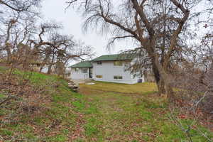 Back of house featuring brick siding, a lawn, and a patio area
