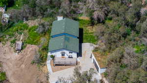 Property featuring a light-colored exterior, an angular green roof, and a front deck