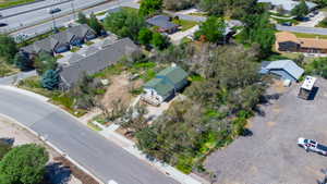 Green-roofed residence set amidst mature trees, featuring a prominent front porch and direct street access