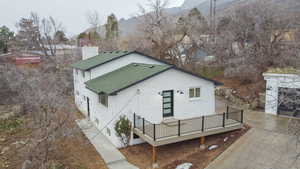 View of front of house with a deck with mountain view, roof with shingles, and a chimney
