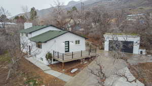 View of front facade featuring a deck with mountain view, an outbuilding, roof with shingles, brick siding, and concrete driveway