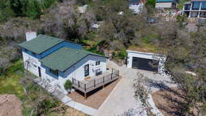 White brick exterior with a green shingle roof, complemented by a raised deck with dark railings