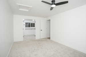 Unfurnished room featuring light colored carpet, a ceiling fan, and a textured ceiling