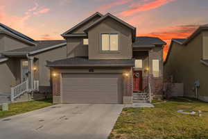 Traditional home featuring brick siding, concrete driveway, a front yard, and stucco siding