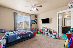 Carpeted bedroom featuring connected bathroom and ceiling fan