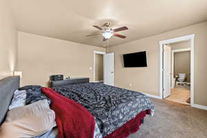 Bedroom featuring light carpet, ceiling fan, and ensuite bathroom