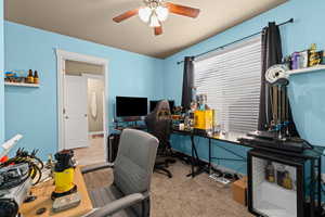 Home office with ceiling fan and light colored carpet