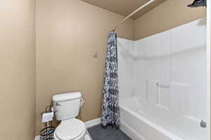 Full bathroom featuring toilet and shower / bath combination with curtain