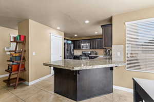 Kitchen with a peninsula, dark wood finish cabinets, stainless steel appliances, a breakfast bar, and decorative backsplash