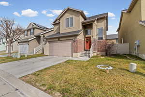 Traditional-style house with brick siding, a garage, concrete driveway, and stucco siding