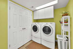 Laundry room featuring cabinet space, separate washer and dryer, and light tile patterned floors