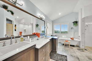 Bathroom with a stall shower, vaulted ceiling, two vanities, double vanity, and a soaking tub