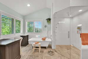 Bathroom with a stall shower, a soaking tub, lofted ceiling, recessed lighting, and a wainscoted wall