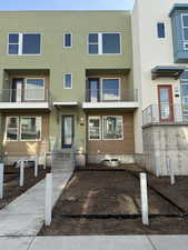 View of front of home featuring stucco siding and a balcony