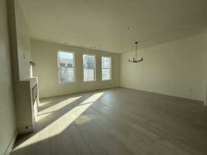Unfurnished living room featuring light wood-style floors and a chandelier