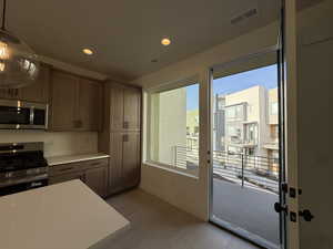 Kitchen featuring stainless steel appliances, light countertops, light wood-style flooring, and hanging light fixtures