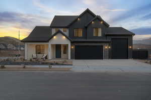 Modern farmhouse with covered porch, concrete driveway, board and batten siding, and a garage