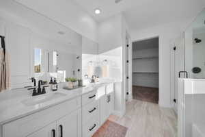 Bathroom with a stall shower, double vanity, and a walk in closet