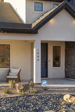 Property entrance featuring stucco siding, a porch, and brick siding