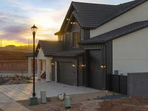 Property exterior at dusk with board and batten siding, driveway, and a tile roof