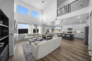 Living room featuring recessed lighting, dark wood-type flooring, a fireplace, and a high ceiling