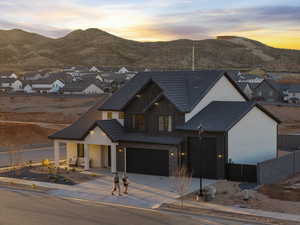 View of front of house featuring a tiled roof, concrete driveway, a mountain view, board and batten siding, and an attached garage