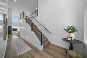 Stairway with a high ceiling, hardwood / wood-style floors, and recessed lighting