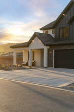 Contemporary house with concrete driveway, board and batten siding, a tiled roof, and a garage