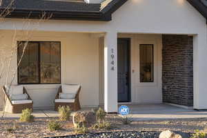 Property entrance featuring a porch, stucco siding, and brick siding