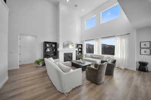 Living area with hardwood / wood-style flooring, a high ceiling, a large fireplace, and recessed lighting