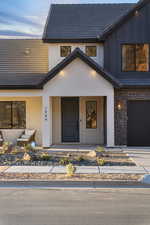 Property entrance featuring a porch, stone siding, board and batten siding, a garage, and a tiled roof