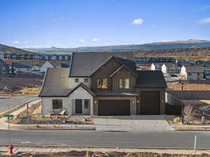 View of front of house with a mountain view, a residential view, brick siding, board and batten siding, and driveway