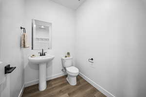 Half bathroom featuring toilet and dark wood-style flooring