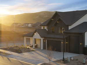 View of front of home featuring board and batten siding, driveway, brick siding, a tile roof, and a mountain view