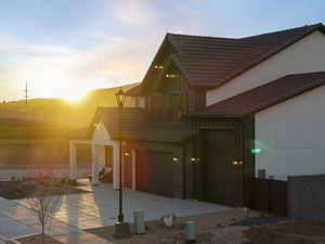 View of front of home featuring brick siding, board and batten siding, a patio area, and a tile roof