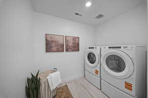 Laundry area featuring washer and clothes dryer and light wood finished floors