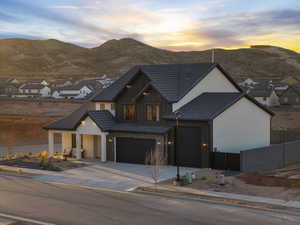 View of front of home with board and batten siding, concrete driveway, an attached garage, a residential view, and a tiled roof