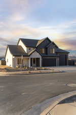 Modern farmhouse style home featuring board and batten siding, a porch, driveway, and stone siding