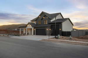 Modern inspired farmhouse featuring driveway, board and batten siding, an attached garage, a tiled roof, and a mountain view