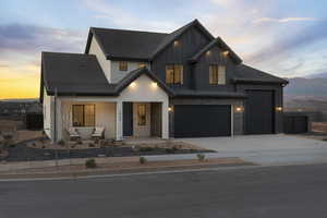 Modern inspired farmhouse featuring concrete driveway, a porch, board and batten siding, and an attached garage