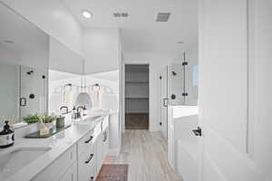 Bathroom featuring a stall shower, double vanity, and a spacious closet