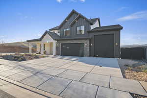 Modern farmhouse with concrete driveway, brick siding, board and batten siding, a garage, and an attached garage