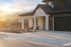 View of front of property with driveway, an attached garage, stone siding, stucco siding, and a tile roof