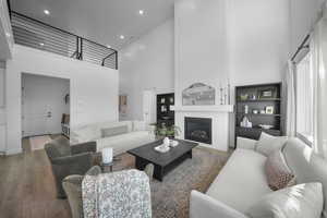 Living area featuring a high ceiling, wood finished floors, a large fireplace, and recessed lighting