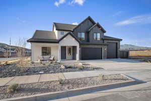 Modern farmhouse style home with a porch, board and batten siding, driveway, an attached garage, and a mountain view