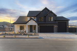 Modern farmhouse with a porch, concrete driveway, board and batten siding, and a garage