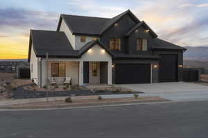 Modern farmhouse featuring driveway, a porch, board and batten siding, brick siding, and a garage